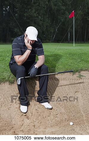 An unhappy golfer sitting at the edge of a sand trap View Large Photo Image Stock Photography - An unhappy golfer sitting at the edge of a sand trap. Fotosearch