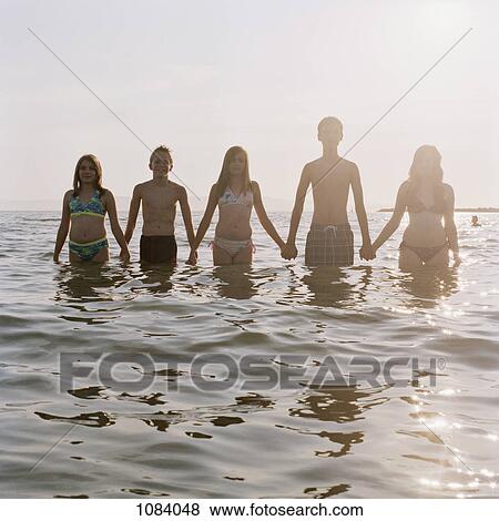 Five friends holding hands in a row while wading in the sea View Large Photo Image Stock Photo - Five friends holding hands in a row while wading in the sea. Fotosearch
