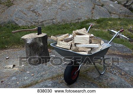 Logs in wheelbarrow and an axe in tree trunk View Large Photo Image Stock Image - Logs in wheelbarrow and an axe in tree trunk. Fotosearch