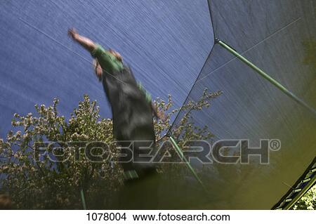 Picture - Low angle view of a child jumping on a trampoline. Fotosearch