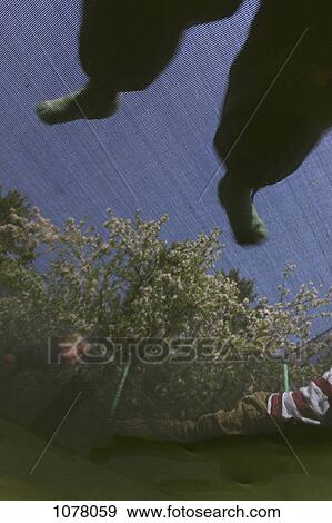Stock Photo - Low angle view of children on a trampoline. Fotosearch