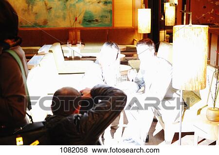 Stock Photo - Man and woman sitting at restaurant table having their photograph taken. Fotosearch