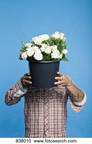 Man holding black bucket of flowers in front of his face View Large Photo Image Stock Image - Man holding black bucket of flowers in front of his face. Fotosearch