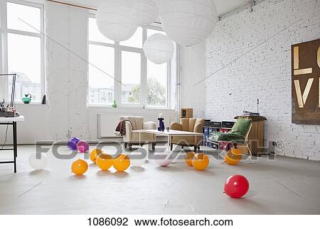 Stock Image - Multi colored balloons on the floor of a modern living room. Fotosearch