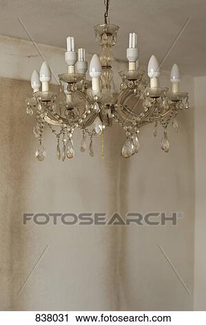 Stock Image - Old and dirty chandelier hanging in bare room. Fotosearch