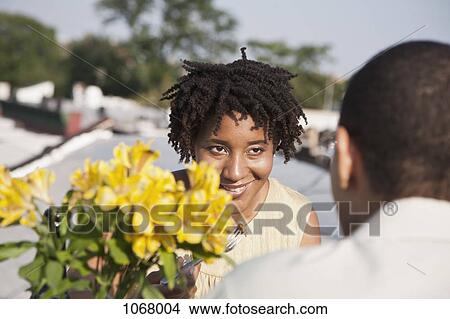 Picture - Over the shoulder view of a couple eating a meal on a rooftop terrace. Fotosearch
