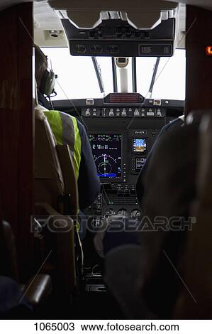 Pilot and co-pilot in the cockpit of an airplane, rear view View Large Photo Image Stock Image - Pilot and co-pilot in the cockpit of an airplane, rear view. Fotosearch