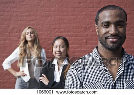 Stock Image - Portrait of a man in front of two female colleagues. Fotosearch