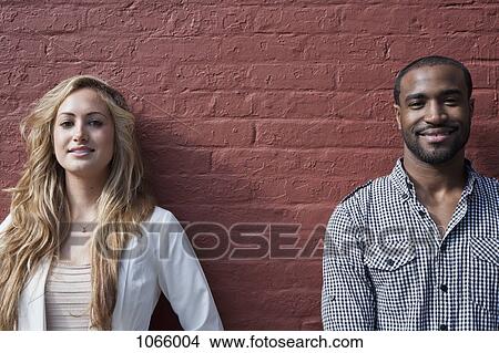 Picture - Portrait of a young woman and a man leaning against a wall. Fotosearch
