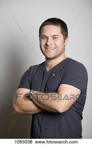 Portrait of confident, smiling young man with arms crossed View Large Photo Image Stock Photo - Portrait of confident, smiling young man with arms crossed. Fotosearch
