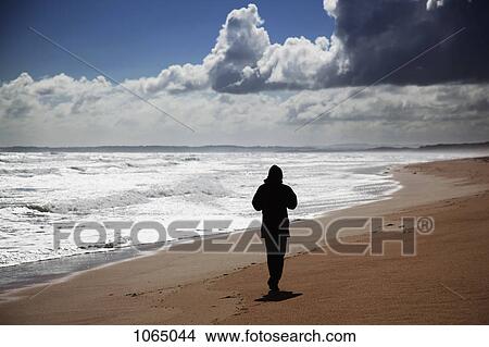 Rear view of a person jogging on a beach View Large Photo Image Picture - Rear view of a person jogging on a beach. Fotosearch