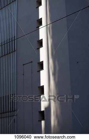 Stock Image - Reflection of light projected onto wall alongside a sequence of window holes. Fotosearch