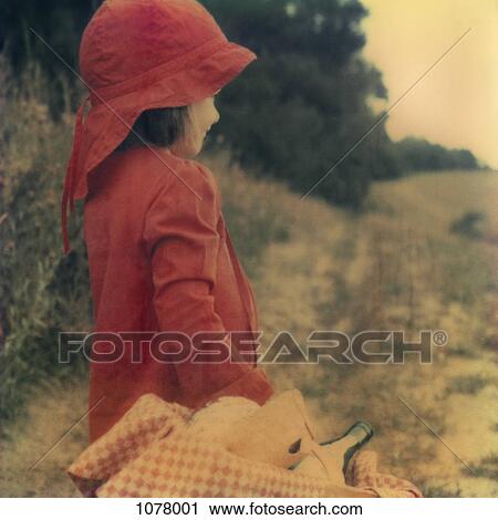 Stock Image - Side view of a young girl holding a picnic basket. Fotosearch