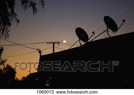 Silhouetted satellite dishes on a rooftop, dusk View Large Photo Image Stock Image - Silhouetted satellite dishes on a rooftop, dusk. Fotosearch