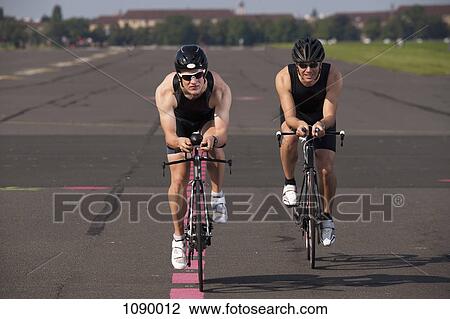 Two cyclists on racing bicycles cycling on a marked road View Large Photo Image Stock Image - Two cyclists on racing bicycles cycling on a marked road. Fotosearch