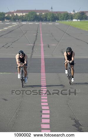 Stock Image - Two cyclists on racing bicycles, front view. Fotosearch