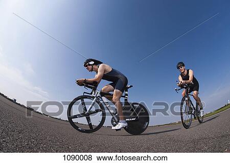 Two cyclists on racing bicycles, side view, low angle view View Large Photo Image Stock Photo - Two cyclists on racing bicycles, side view, low angle view. Fotosearch