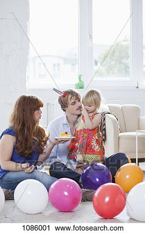 Stock Image - Two young parents celebrating their daughter's birthday with her. Fotosearch
