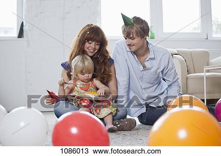 Stock Image - Two young parents with their daughter, celebrating her birthday. Fotosearch