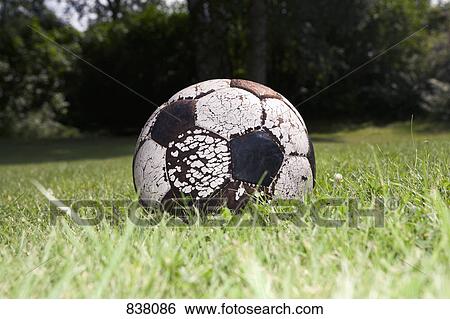 Stock Photograph - Worn soccer ball on grass. Fotosearch
