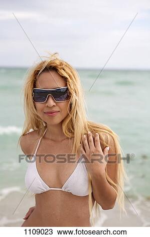 A beautiful young woman in a bikini and sunglasses at the beach View Large Photo Image Stock Image - A beautiful young woman in a bikini and sunglasses at the beach. Fotosearch