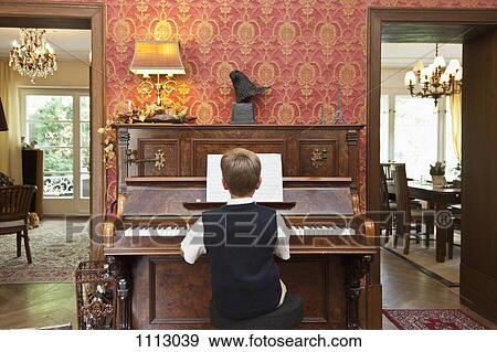 Stock Photo - A boy practicing on an old-fashioned upright piano. Fotosearch