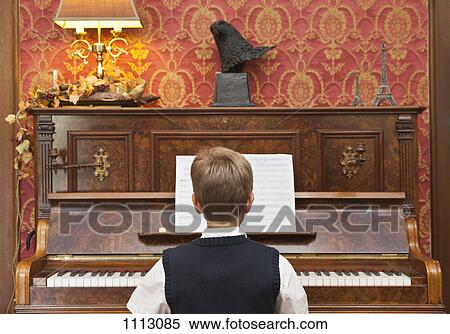 A boy practicing on an upright piano View Large Photo Image Stock Photography - A boy practicing on an upright piano. Fotosearch