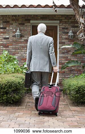 A businessman arriving home from a trip View Large Photo Image Stock Photograph - A businessman arriving home from a trip. Fotosearch