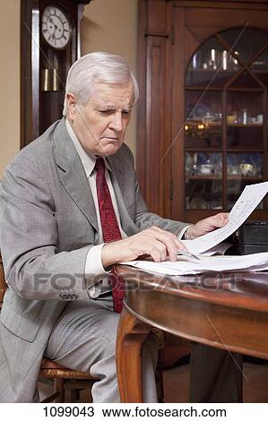 A businessman considering some paperwork at home View Large Photo Image Stock Image - A businessman considering some paperwork at home. Fotosearch