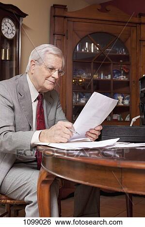 A businessman reading through paperwork at home View Large Photo Image Stock Photograph - A businessman reading through paperwork at home. Fotosearch
