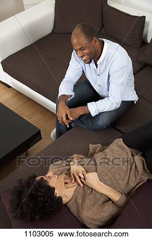 Stock Photography - A cheerful laughing couple relaxing on a sofa. Fotosearch