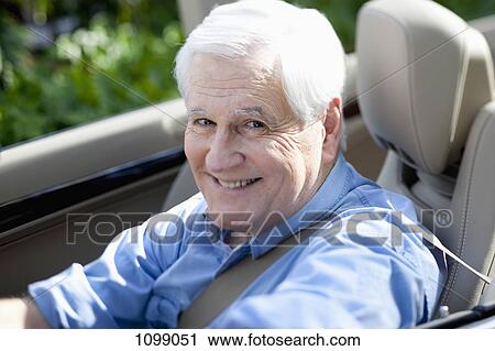 Stock Image - A cheerful senior man driving a convertible sports car. Fotosearch