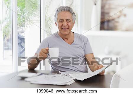 A cheerful senior man reading the paper and drinking coffee View Large Photo Image Stock Photograph - A cheerful senior man reading the paper and drinking coffee. Fotosearch