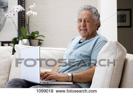 A cheerful senior man using a laptop at home View Large Photo Image Stock Photo - A cheerful senior man using a laptop at home. Fotosearch