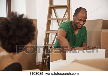 Stock Photography - A couple packing moving boxes, focus on man. Fotosearch