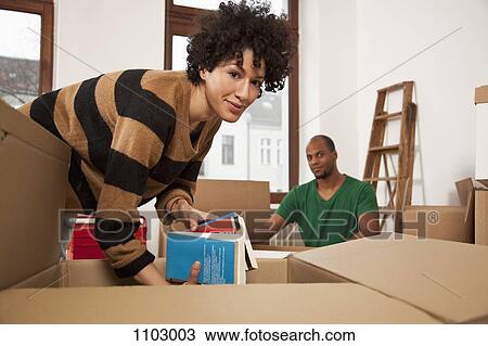 Stock Image - A couple packing moving boxes. Fotosearch