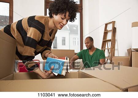Stock Image - A couple packing moving boxes. Fotosearch