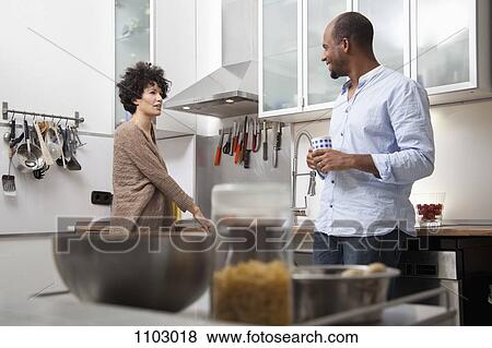 A couple standing in an apartment kitchen View Large Photo Image Stock Photo - A couple standing in an apartment kitchen. Fotosearch