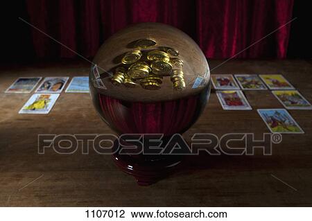A crystal ball with gold coins in the reflection and tarot cards in background View Large Photo Image Stock Image - A crystal ball with gold coins in the reflection and tarot cards in background. Fotosearch