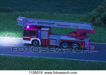 A diorama of a miniature toy fire truck driving on a road at night View Large Photo Image Stock Photo - A diorama of a miniature toy fire truck driving on a road at night. Fotosearch