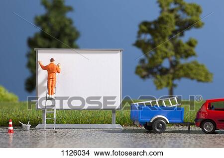 A diorama of a miniature worker billboard posting View Large Photo Image Picture - A diorama of a miniature worker billboard posting. Fotosearch
