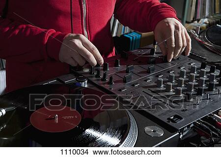 Picture - A DJ adjusting knobs on a sounder mixer, detail of hands. Fotosearch
