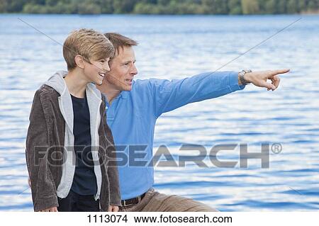 A father pointing something out to his son, outdoors View Large Photo Image Picture - A father pointing something out to his son, outdoors. Fotosearch