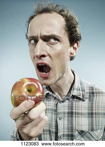 A frowning man preparing to bite into an apple View Large Photo Image Stock Image - A frowning man preparing to bite into an apple. Fotosearch
