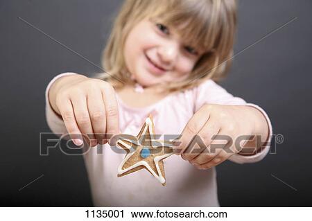 A girl holding out up a star shaped Christmas cookie View Large Photo Image Stock Image - A girl holding out up a star shaped Christmas cookie. Fotosearch