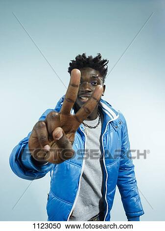 A hip young man flashing the peace sign, focus on hand View Large Photo Image Stock Image - A hip young man flashing the peace sign, focus on hand. Fotosearch