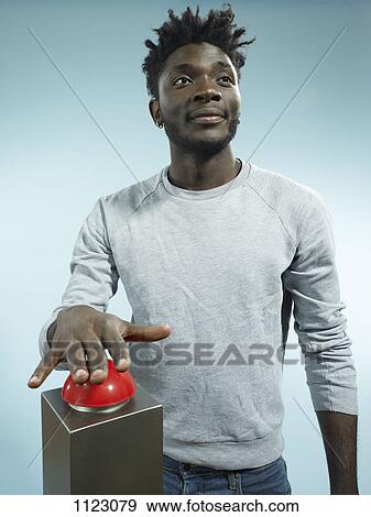 Stock Photo - A hip young man with his hand poised above a red game show buzzer. Fotosearch