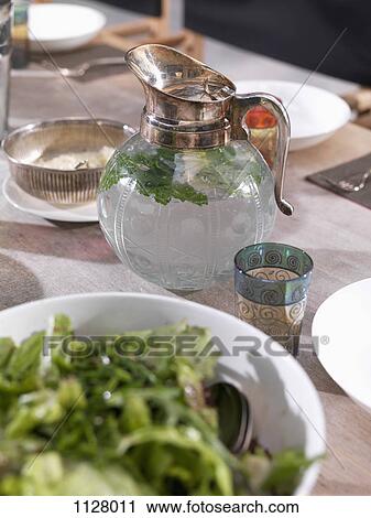Stock Image - A jug of water and a glass on a dining table. Fotosearch