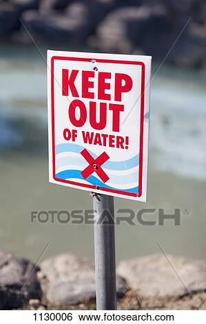 Stock Photograph - A Keep Out of Water sign posted on a rocky beach. Fotosearch