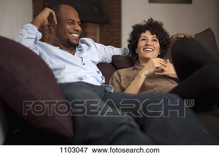 A laughing couple relaxing together on a sofa View Large Photo Image Stock Photo - A laughing couple relaxing together on a sofa. Fotosearch